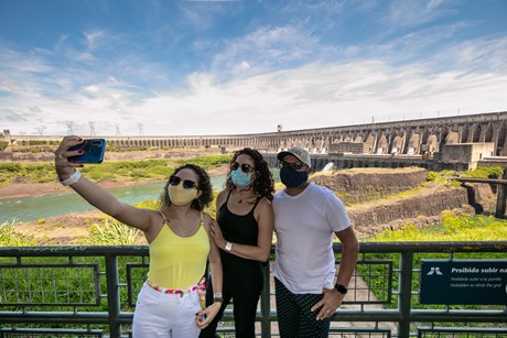 Turistas com máscaras de proteção contra a covid-19 fazem selfie no Mirante Central da usina hidrelétrica Itaipu. 